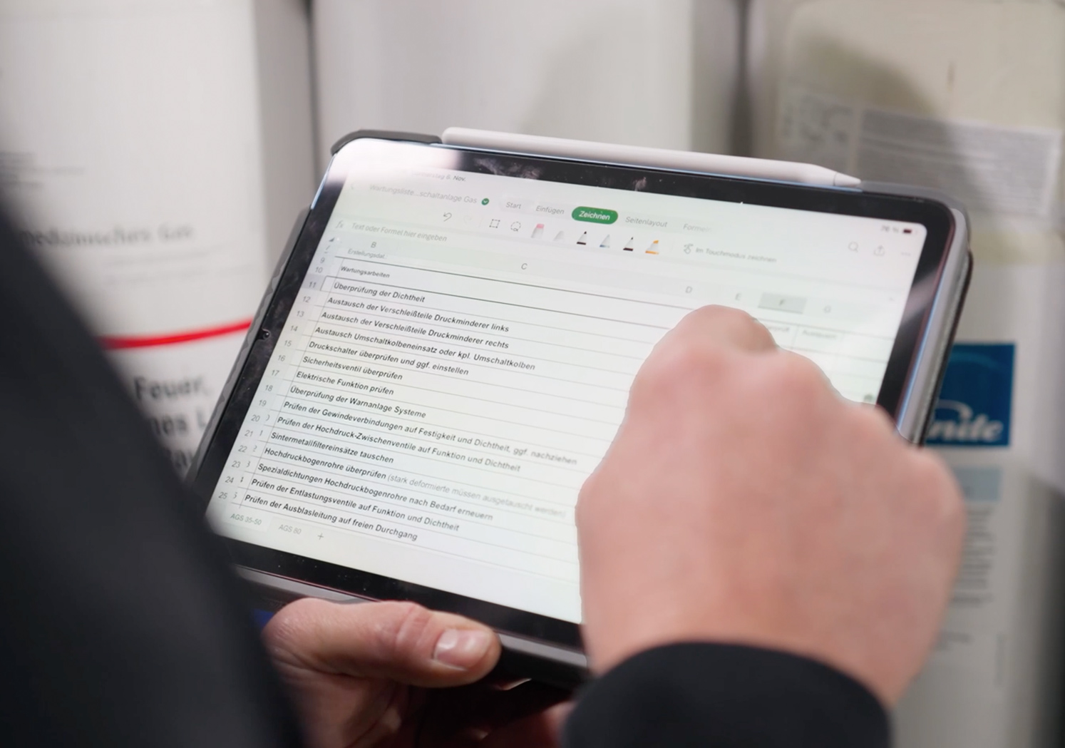 Mitarbeiter prüft eine digitale Checkliste auf einem Tablet während einer technischen Kontrolle in einer Medizintechnik-Umgebung.